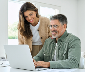 Happy couple using their laptop to pay dues